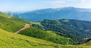 Yeşil dağ Vadisi konut binalar yüksek dağlarla çevrili yüksekliğini görünümden. Karla kaplı dağ zirveleri ufukta.