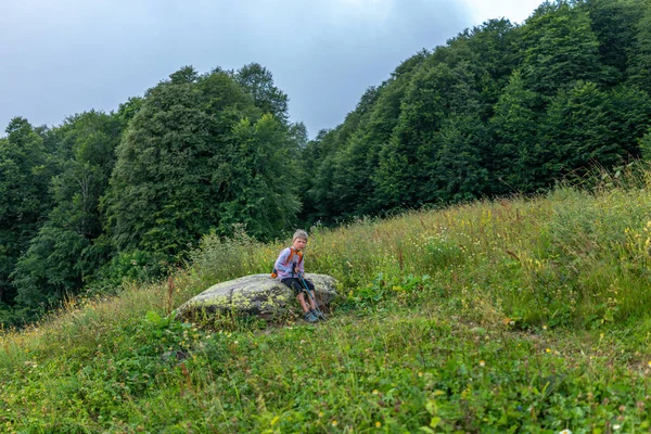 Boy Traveler Backpack Trekking Poles Resting Stone Mountainside — Stock Photo, Image