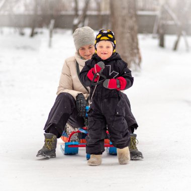 Keçe çizmeler güçlü küçük çocuk annesi bir kızak üzerinde taşır..
