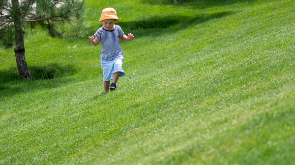 Ένα μικρό αγόρι τρέχει πάνω σε καταπράσινο λόφο — Φωτογραφία Αρχείου