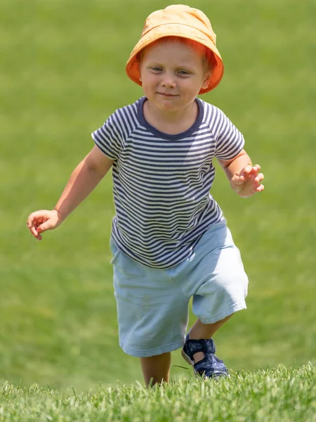 Ένα μικρό αγόρι τρέχει πάνω σε καταπράσινο λόφο — Φωτογραφία Αρχείου