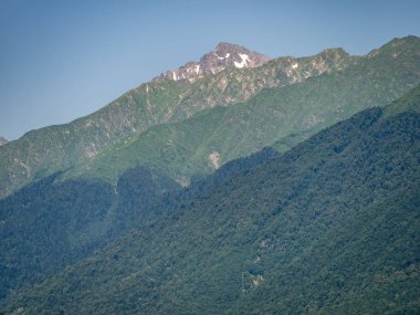 Güneşli bir gün, yaz aylarında yeşil dağların zirveleri karla kaplı