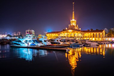 Deniz İstasyonu, su yansıması ile gece ışık ile aydınlatılmış Soçi. Yat ve tekne iskelede
