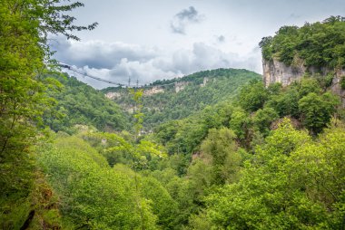 Bizimhava asma köprü bulutlu bir günde bir uçurumun üzerinden. Yeşil orman çevresinde. Skypark, Sochi, Rusya Federasyonu.