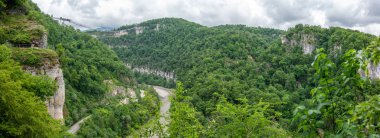 Bizimhava asma köprü ile bulutlu bir günde bir nehir ve serpantin yolda bir uçurumun üzerinden bir geçit üzerinde. Panorama. Skypark, Sochi, Rusya Federasyonu.