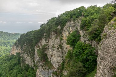 Dağ bir dik kayalık yamaç ve vadi yeşil orman aşağıda kalın. Konut ve deniz uzaktan görülebilir