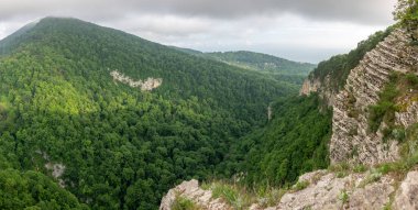 Dağ bir dik kayalık yamaç ve vadi yeşil orman aşağıda kalın. Konut ve deniz uzaktan görülebilir