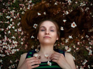 Kız beyaz çiçeklerle kaplı çim üzerinde yalan