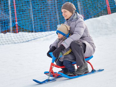 Mutlu anne oğluyla bir kızak dağdan sürmek.