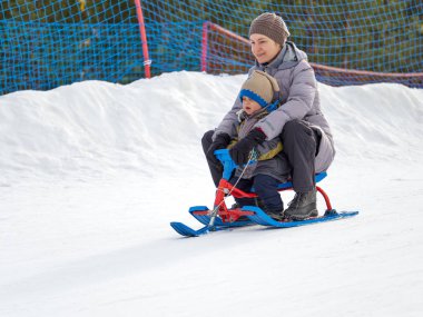 Mutlu anne oğluyla bir kızak dağdan sürmek.