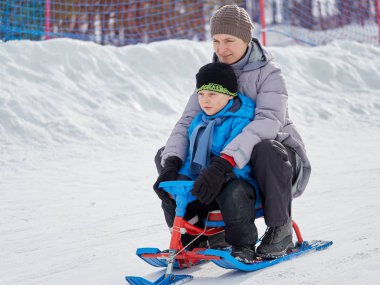 Mutlu anne oğluyla bir kızak dağdan sürmek.