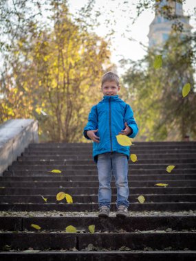 Çocuk adımları yapraklarda sonbahar parkta atar.