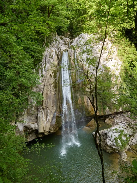 Una alta cascada cae de un acantilado en un lago claro — Foto de Stock