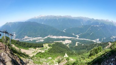 Yüksek dağlarla çevrili yeşil vadi konut evler üzerinde göster