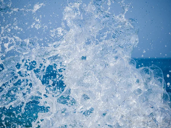 Salpicos de água contra o mar em um dia ensolarado de verão — Fotografia de Stock