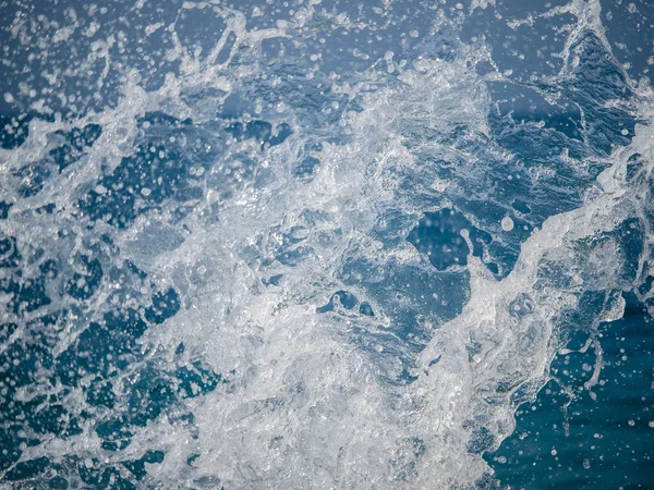 Salpicaduras de agua contra el mar en un soleado día de verano — Foto de Stock