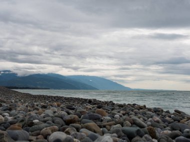 Bulutlu bir yaz veya sonbahar gününde deniz ve çakıl Sahili.