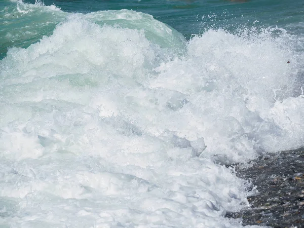 Splashes of water and foam against the sea on a sunny summer day — Stock Photo, Image