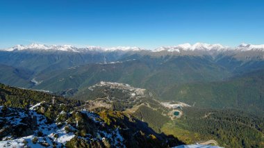Aibga sıradağlarının tepesinden teleferik li kayak merkezine panoramik manzara. Vadi karlı yamaçları ile yüksek dağlarla çevrilidir.