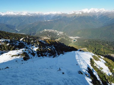 Karla kaplı sıradağların ve önündeki yeşil vadinin manzarası