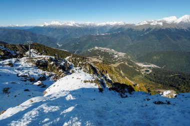 Önündeki yeşil vadiye teleferik ile karla kaplı dağ dan görünümü