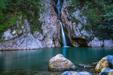 Yüksek bir şelale uçurumdan açık bir göle düşüyor.