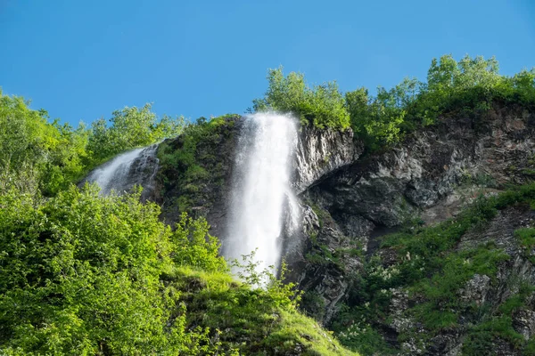 En yüksek şelale ile yeşil dağların manzarasını sunmaktadır. Açık mavi gökyüzü