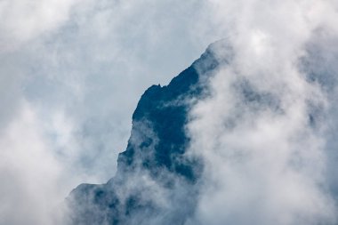 Ormanlı yamaçlarda ve bulutlarda gizlenmiş doruklara sahip yüksek dağlar.