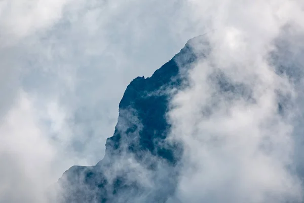 Altas montanhas com encostas florestadas e picos escondidos nas nuvens . — Fotografia de Stock