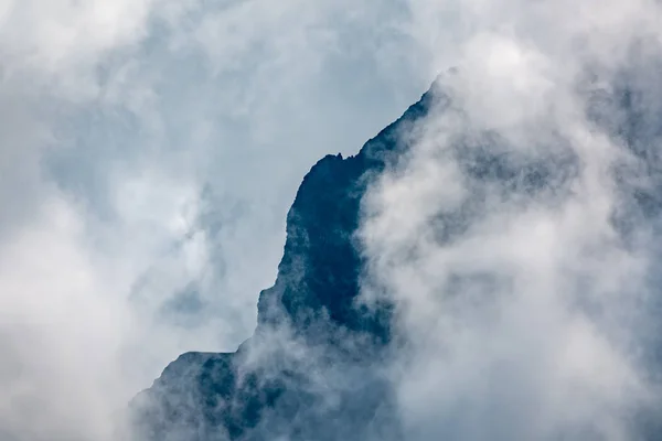 Altas montanhas com encostas florestadas e picos escondidos nas nuvens . — Fotografia de Stock