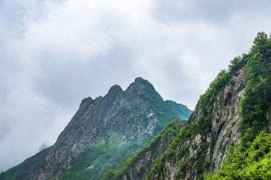 Bulutlarda yüksek kayalık dağ zirvesi.