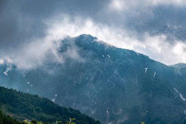 Bulutlarda yüksek kayalık dağ zirvesi.