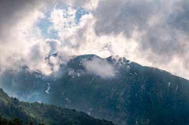 Bulutlarda yüksek kayalık dağ zirvesi.