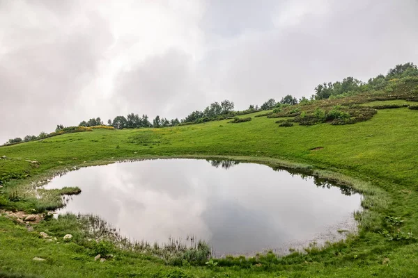Vue d'un lac de montagne avec eau claire et reflet lors d'une journée nuageuse en été . — Photo