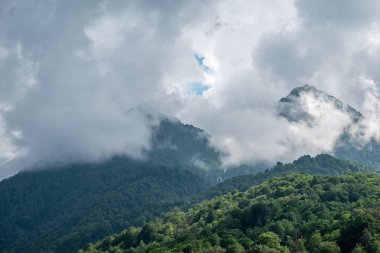Sis ve bulutlar yüksek bir şelale ile yeşil dağlar.