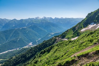 Açık bir yaz gününde yüksek dağlarla çevrili Yeşil Vadi'nin manzarası