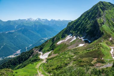 Yeşil yamaçlara ve karlı doruklara sahip yüksek dağlar.