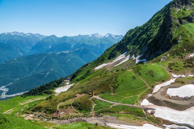 Yeşil yamaçlara ve karlı doruklara sahip yüksek dağlar.