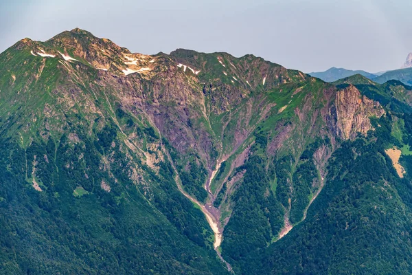 Yeşil yamaçlara ve karlı doruklara sahip yüksek dağlar.
