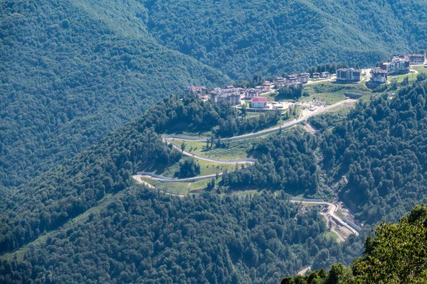 Hotel in den Bergen inmitten des grünen Waldes. Serpentinenstraße in den Bergen. Krasnaja Poljana, Sotschi, Russland — Stockfoto