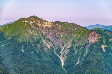 Yeşil yamaçlara ve karlı doruklara sahip yüksek dağlar.