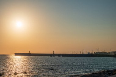 Dalgakıran ve deniz feneri olan açık gökyüzü ve parlak gün batımı. Boşluk arkaplanı kopyala