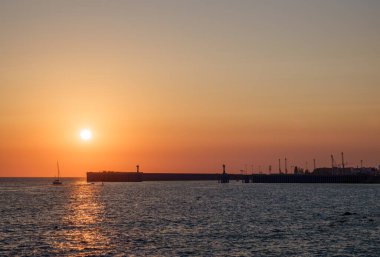 Deniz üzerinde güzel sarı ve turuncu gün batımı. Güneş denizin üzerinde batıyor. Gün batımında deniz limanının silueti. Dramatik Günbatımı Gökyüzü.