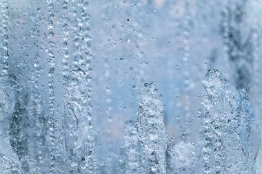 Arka planda hafif su damlaları. Çeşme, bulutlu gökyüzüne karşı bir su jeti.