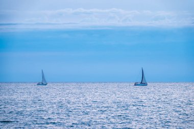 Mavi sakin denizde iki yelkenli yatı. Huzurlu sularda yatlar.