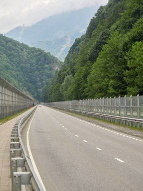 Gürültülü modern yol yeşil dağlar arasındaki çitleri yalıtıyor.