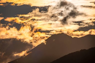Dağ silueti turuncu bulutlu gün batımında güzel dağlarda gün batımı