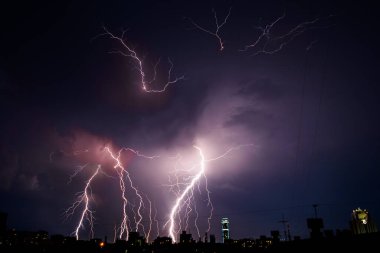 Büyük şehrin üzerindeki güzel, güçlü şimşeğin, fermuarın ve fırtınanın, soyut arka plan, parlak elektrik şimşekleri, gök gürültüsü ve şimşeklerin olduğu koyu mavi gökyüzü, kötü hava kavramı.