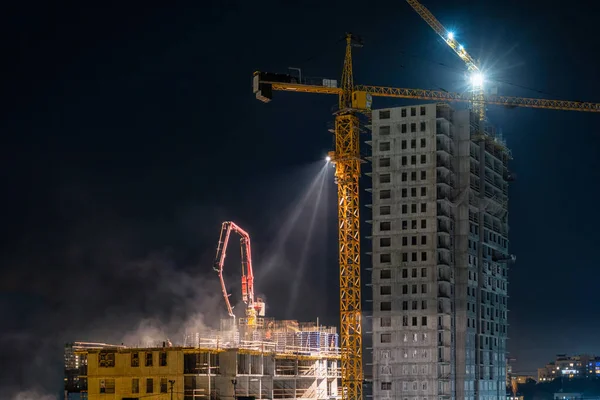 Bir inşaat sahasında gece taşları dökülüyor. Şehirdeki bir şantiyede gece işi. Gece bir inşaat alanında kule vinci.