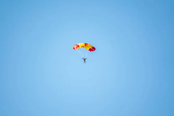 澄んだ空を背景に 一人のパラシュートがゆっくりと低高度に浮かんでいます スカイダイビング スポーツや極端なリラクゼーションのアクティブな種類 — ストック写真